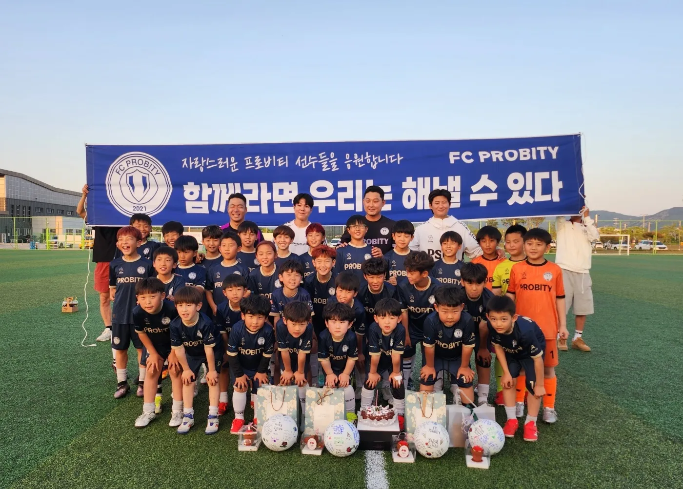 FC Probity squad and coaches on the pitch in front of the club banner